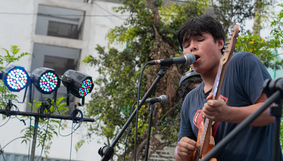 Vocalista de Arena Surf frente al micrófono con su guitarra naranja.