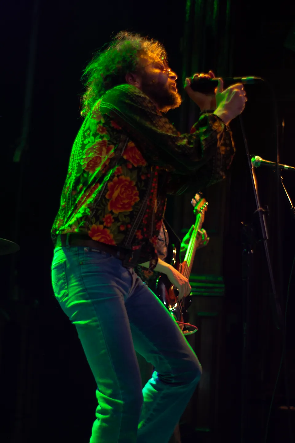 Vocalista de Volcano cantando bajo la iluminación verde del escenario.